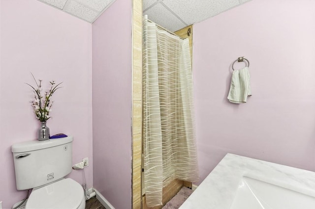 full bath featuring a drop ceiling, toilet, and a shower with curtain