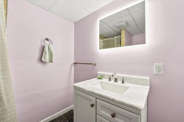 bathroom featuring a paneled ceiling, baseboards, vanity, and tile patterned floors
