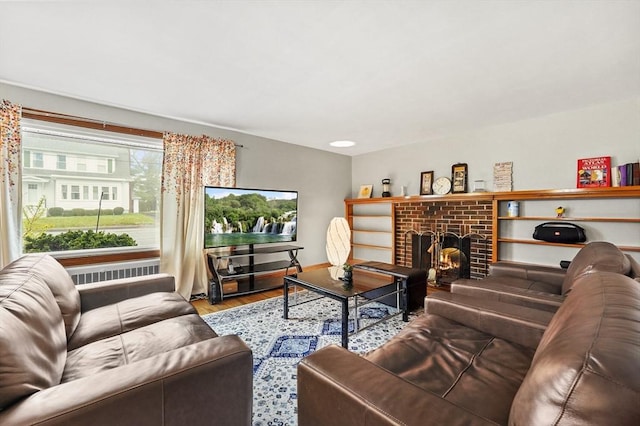 living area with wood finished floors, a brick fireplace, and baseboards