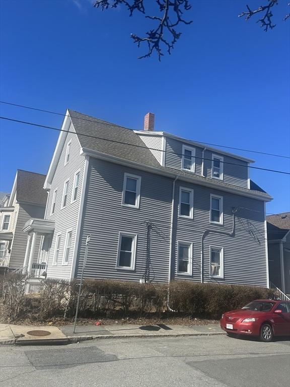 view of front facade with roof with shingles and a chimney