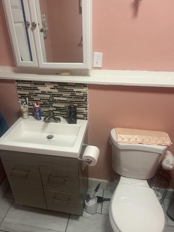 bathroom featuring toilet, tile patterned flooring, vanity, and tasteful backsplash