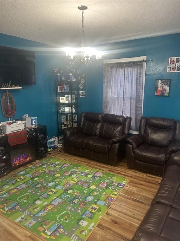 living room with a textured ceiling, a chandelier, and wood-type flooring