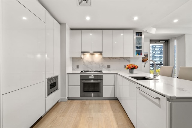 kitchen with sink, kitchen peninsula, white cabinets, and appliances with stainless steel finishes