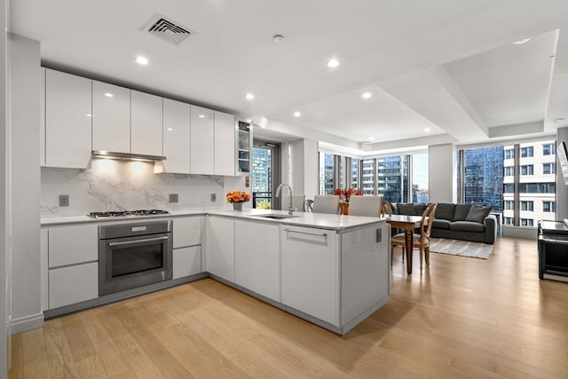 kitchen with white cabinetry, appliances with stainless steel finishes, kitchen peninsula, and sink