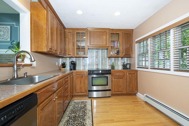 12 Crosby, Webster, MA 01570 - kitchen featuring a baseboard heating unit, stainless steel appliances, a sink, brown cabinetry, and light wood finished floors