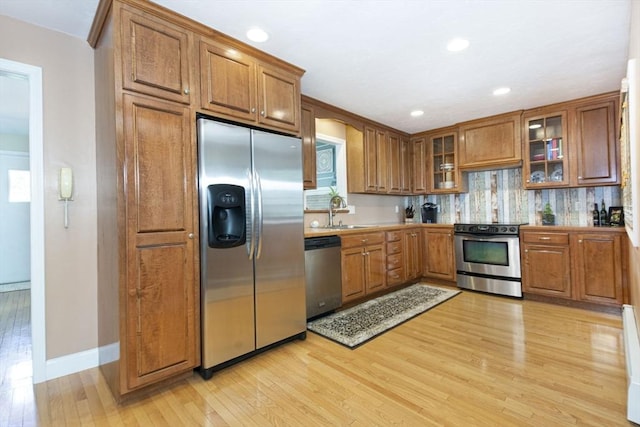 12 Crosby, Webster, MA 01570 - kitchen featuring appliances with stainless steel finishes, brown cabinetry, a sink, light wood finished floors, and glass insert cabinets