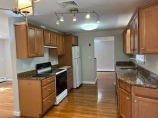 kitchen featuring dark stone counters, light hardwood / wood-style floors, sink, and white appliances