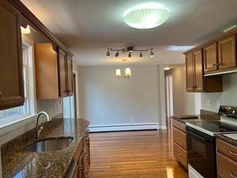 kitchen with light wood-type flooring, sink, a baseboard radiator, hanging light fixtures, and white electric range