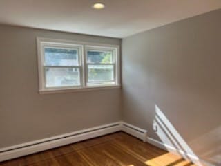 unfurnished room featuring hardwood / wood-style floors and a baseboard radiator