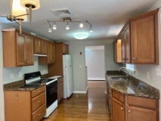 kitchen featuring white appliances, light hardwood / wood-style floors, sink, and dark stone counters