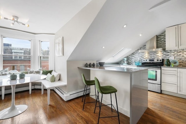 kitchen featuring white cabinets, wall chimney exhaust hood, a kitchen bar, backsplash, and stainless steel range with electric stovetop