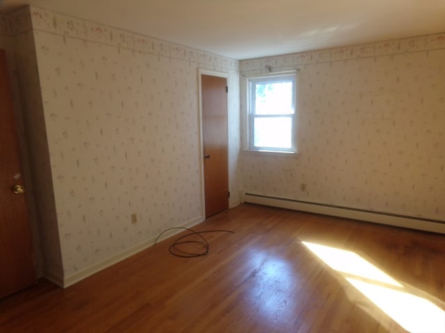 empty room featuring wood-type flooring and baseboard heating