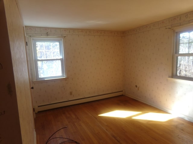 unfurnished room with a baseboard heating unit and hardwood / wood-style flooring