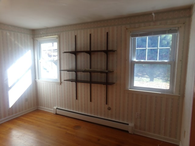 empty room with light wood-type flooring and a baseboard heating unit