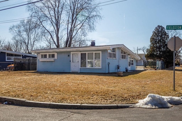 view of front facade with a front lawn, fence, and a chimney