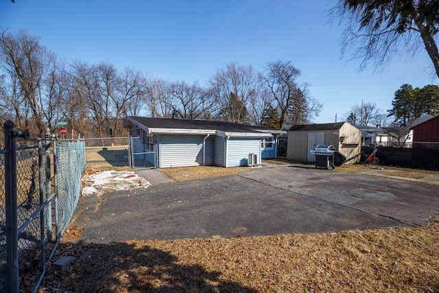 garage featuring a gate, a storage shed, driveway, and fence