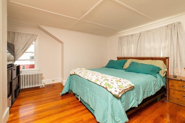 bedroom with baseboards, wood finished floors, and radiator