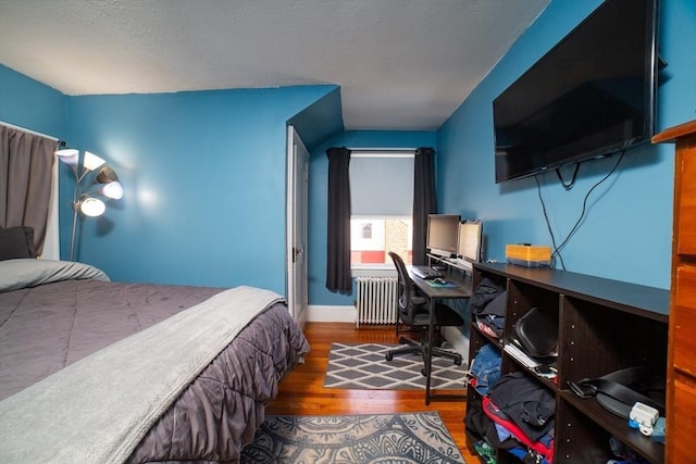 bedroom with baseboards, radiator, and wood finished floors