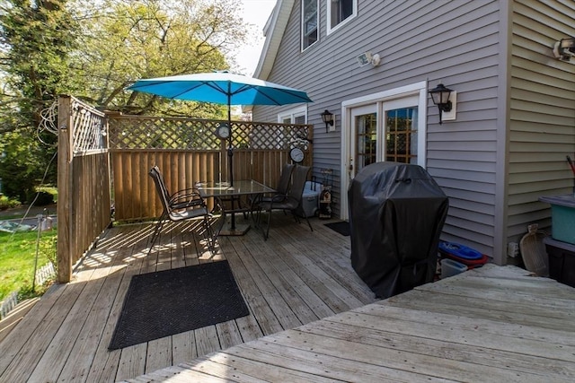 wooden deck featuring outdoor dining area and a grill