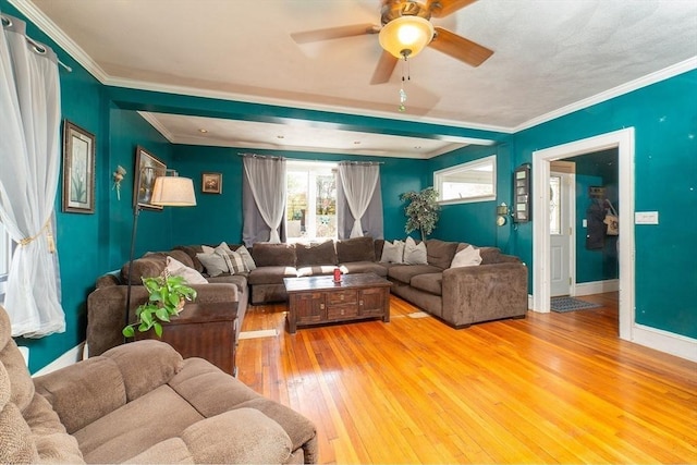 living room featuring a ceiling fan, baseboards, ornamental molding, and light wood-type flooring