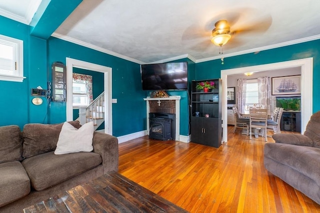 living room with crown molding, stairs, baseboards, hardwood / wood-style flooring, and a ceiling fan