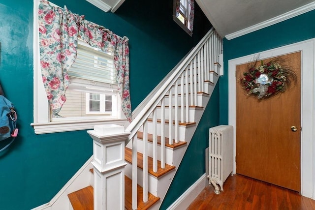 stairway featuring ornamental molding, wood finished floors, and radiator