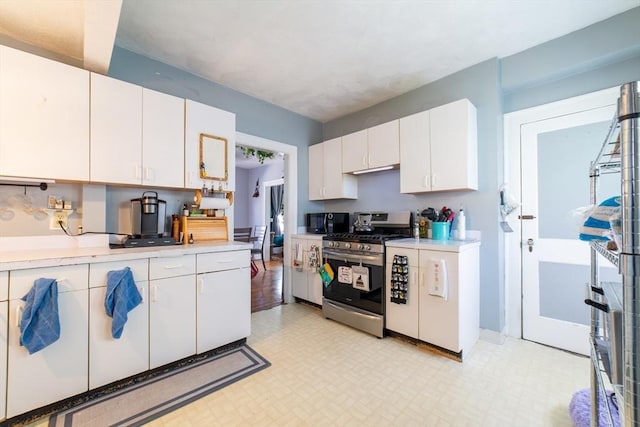 kitchen featuring black microwave, light floors, stainless steel gas range, light countertops, and white cabinets