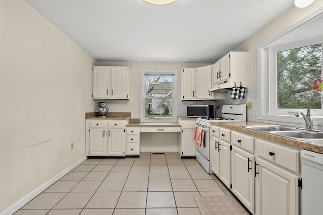 kitchen featuring a sink, backsplash, white appliances, white cabinets, and built in study area