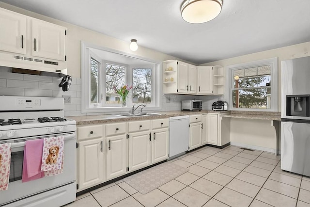 kitchen with open shelves, under cabinet range hood, light countertops, white appliances, and a sink