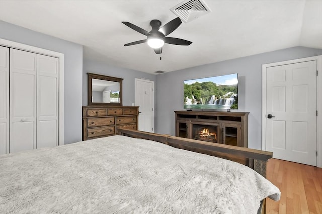 bedroom featuring visible vents, multiple windows, light wood-type flooring, and a lit fireplace