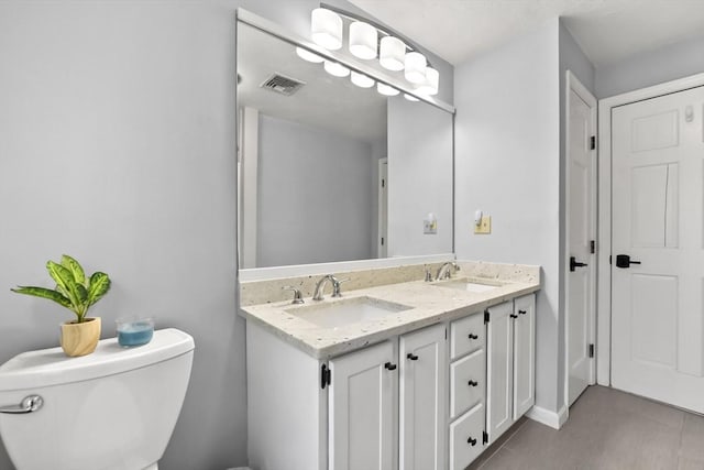 bathroom with double vanity, visible vents, toilet, and a sink