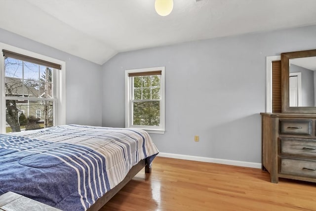 bedroom featuring vaulted ceiling, light wood-style floors, and baseboards