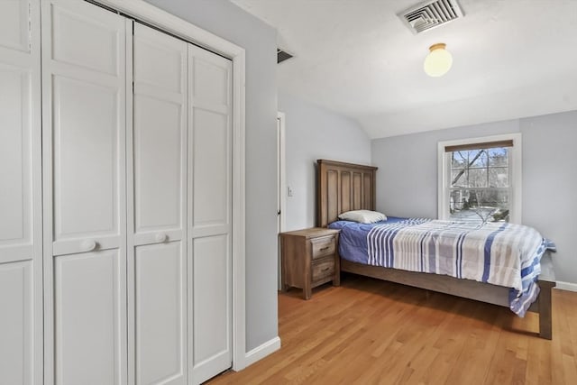 bedroom featuring visible vents, light wood-style floors, and vaulted ceiling