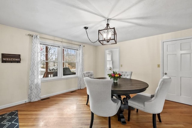 dining area featuring a notable chandelier, wood finished floors, and baseboards