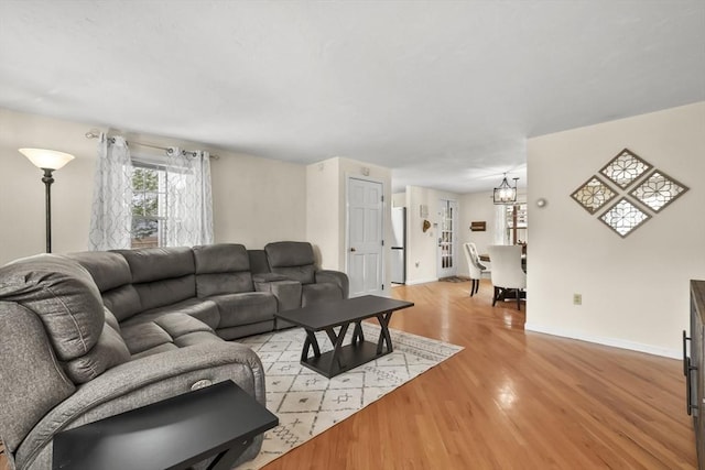 living area with a notable chandelier, baseboards, and light wood finished floors