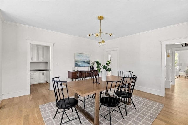 dining space featuring light wood-style floors, baseboards, crown molding, and a notable chandelier