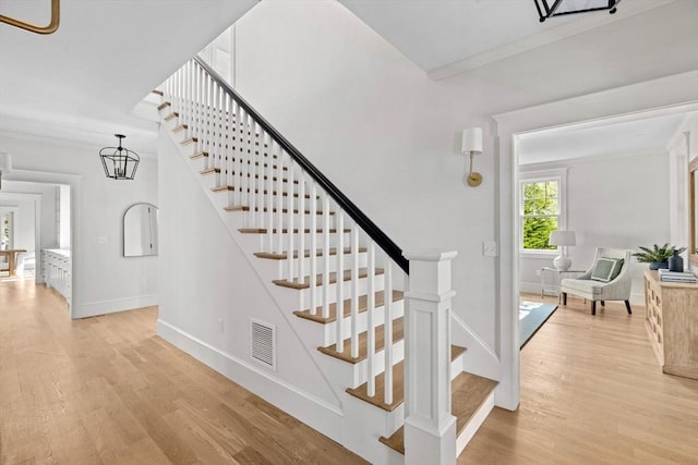 stairway with baseboards, ornamental molding, wood finished floors, and visible vents