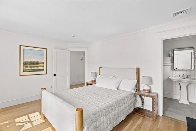 bedroom with crown molding, visible vents, and wood finished floors
