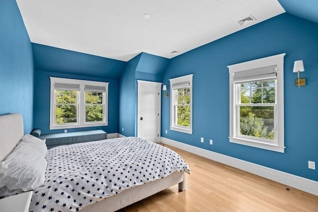 bedroom with baseboards, vaulted ceiling, wood finished floors, and visible vents