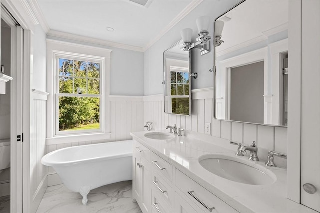 bathroom with a freestanding bath, wainscoting, a sink, and marble finish floor