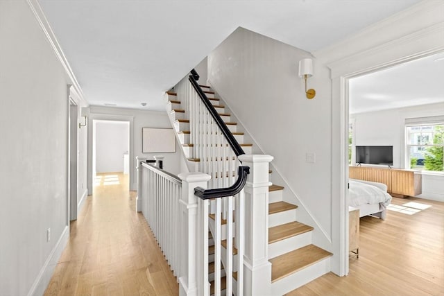 stairway featuring crown molding, baseboards, and wood finished floors