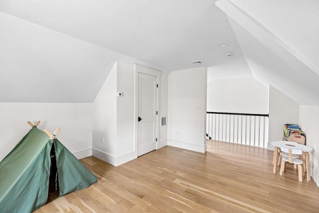 bonus room with baseboards, lofted ceiling, wood finished floors, and visible vents