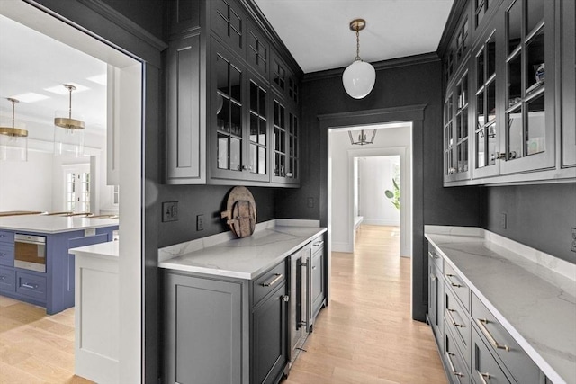kitchen featuring light stone counters, pendant lighting, light wood finished floors, and glass insert cabinets