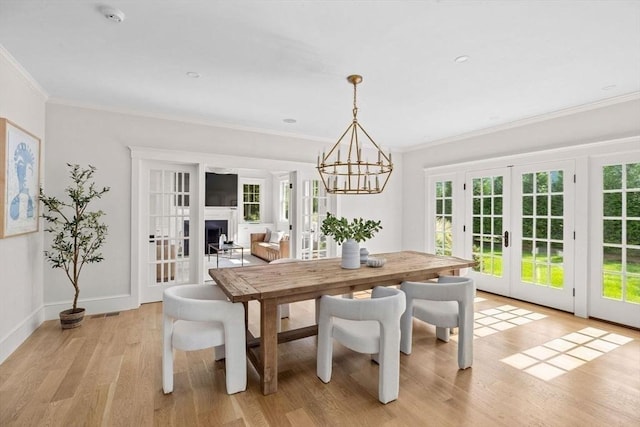 dining room with a chandelier, a wealth of natural light, french doors, and light wood-type flooring
