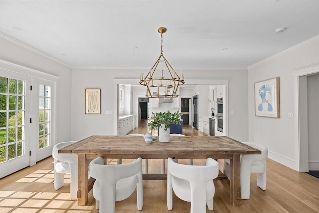 dining space with baseboards, ornamental molding, light wood finished floors, and a notable chandelier