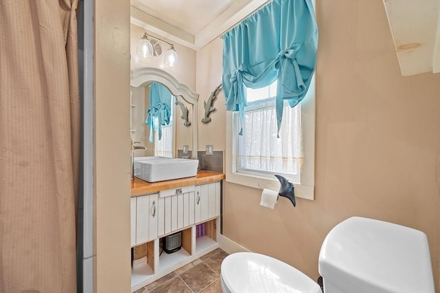 bathroom featuring tile patterned flooring, crown molding, baseboards, toilet, and vanity