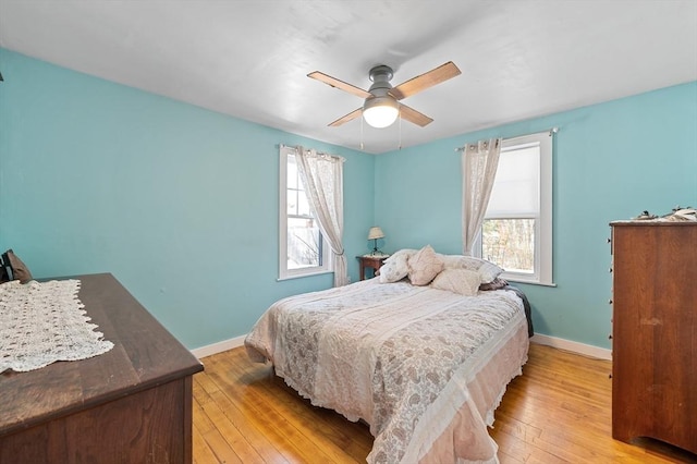 bedroom with a ceiling fan, light wood-style floors, and baseboards