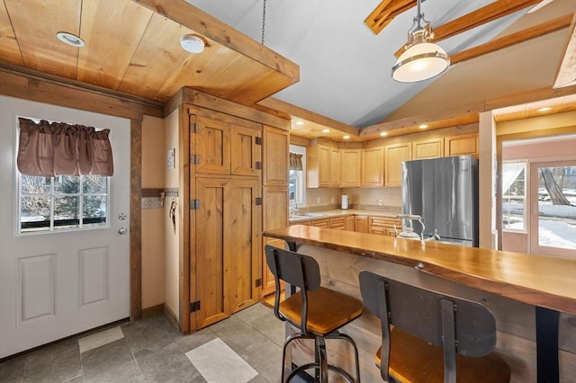 kitchen with plenty of natural light, lofted ceiling, light countertops, and freestanding refrigerator