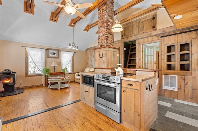 kitchen with a wood stove, stainless steel electric stove, light wood-style floors, built in microwave, and vaulted ceiling with beams