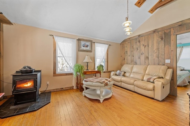 living room featuring a wood stove, wood-type flooring, and vaulted ceiling